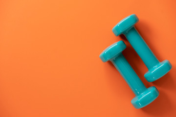 dumbbell and orange yoga mat on table, fitness healthy and sport concept