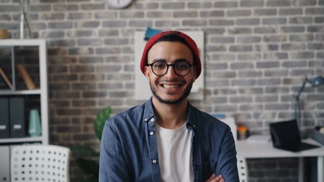 Slow motion portrait of successful business owner creative handsome guy smiling looking at camera standing in office alone. Start-up, millennials and creativity concept.