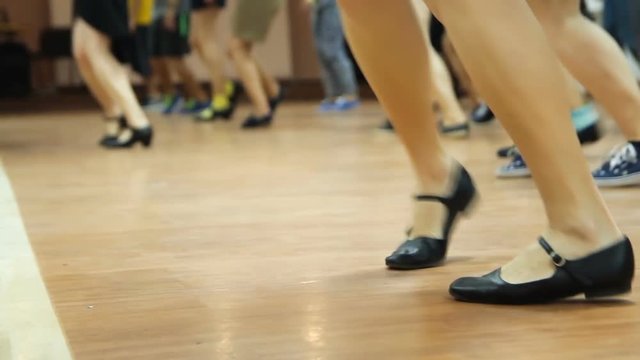 Looped video of dancing legs close-up. Dancers learning new moves. Woman teaching solo jazz swing dance.