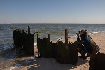 Frau macht Fotos von einer Buhne an der Nordsee