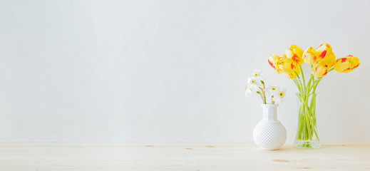 Home interior with decor elements. Yellow tulips in a glass vase on a wooden table