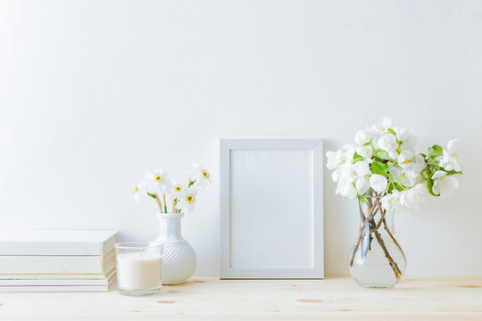 Home interior with decor elements. White frame, white spring flowers in a vase, interior decoration