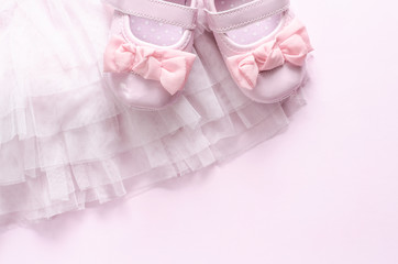 Dress of a little girl, pink tulle, shoes with ribbon on pink background.
