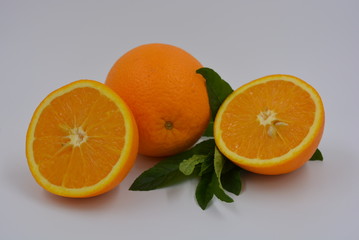 Bright two orange halves of cut ripe and large juicy orange and a branch of fresh mint. Healthy food and fruit, health and sport.