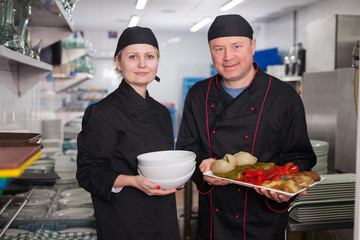 Male chef with female assistant presenting cooked dish