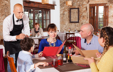 Waiter taking order of family at restaurant