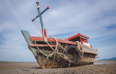 Wreck wooden fishery boat on the beach.