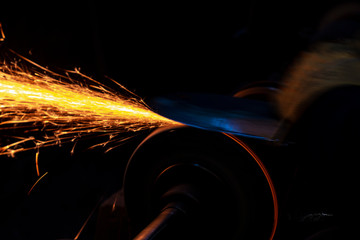 Fire sparks on a black background during workers sharpen a knife.