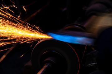 Fire sparks on a black background during workers sharpen a knife.