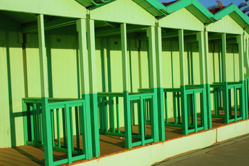 bathing huts at the sea in green color. booths for changing clothes during the summer season on beach holidays. changing rooms arranged in a regular and orderly row