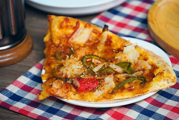 Piece of pizza on white dish plate lay on the table in the restaurant.