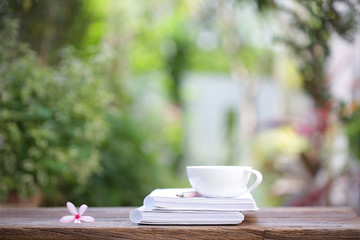 White coffee cup and notebooks on wooden table at outdoor