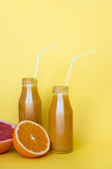 Fresh orange juice with oranges on yellow background. Copy space