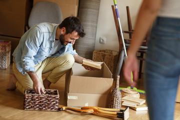 Young man unpacking cardboard boxes at new home.Moving house.