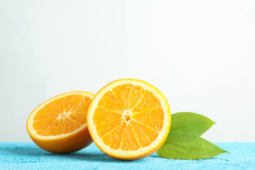 Halves orange with leaves on blue table against white background, space for text