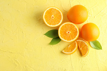 Fototapeta na wymiar Flat lay composition with ripe oranges and leaves on color background. Top view, space for text