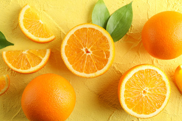 Flat lay composition with ripe oranges and leaves on color background, closeup