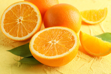 Ripe oranges with leaves on color background, closeup