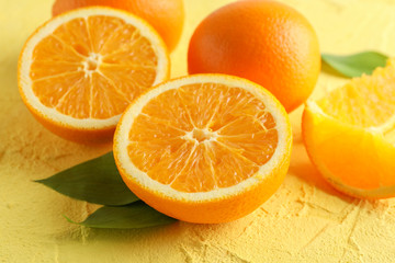 Ripe oranges with leaves on color background, closeup