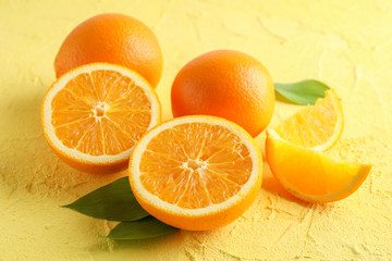 Ripe oranges with leaves on color background, closeup