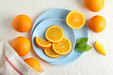 Plates with orange slices and kitchen towel on white background. Top view