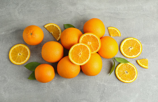 Many ripe oranges and leaves with space for text on grey table, top view © Atlas