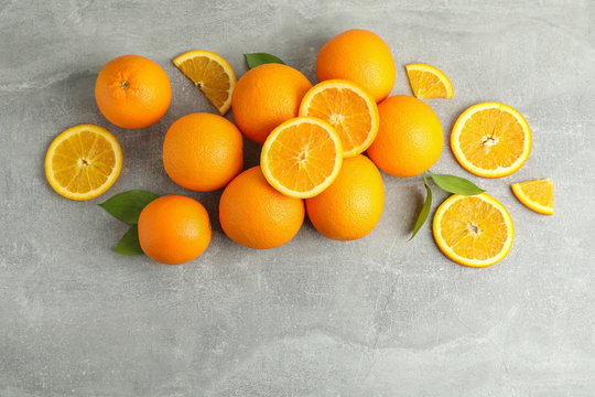 Many ripe oranges and leaves with space for text on grey table, top view © Atlas