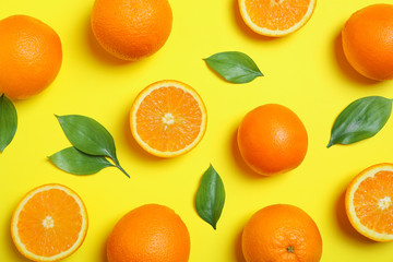 Flat lay composition with oranges and leaves on yellow background. Citrus food