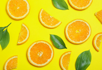 Flat lay composition with oranges and leaves on yellow background. Closeup