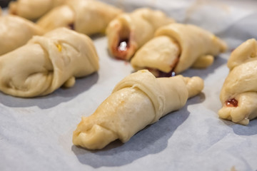 Raw buns with plum jam before baking. Close up view, selective focus. Confectionery cuisine.