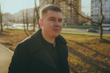 Man standing beside trees in sunny day Portrait of young man in casual clothes posing among trees...