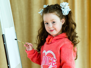 portrait of a little girl with a brush near the easel