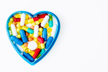 Heart with assorted pharmaceutical medicine pills, tablets, capsules on white background top view. Medical pharmacy, cardiology, healthy heart concept. Copy space