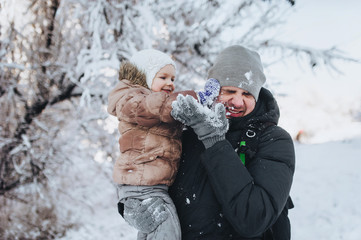 Fototapeta na wymiar Father and daughter indulge in the winter and throw snow. Family fun with a child.