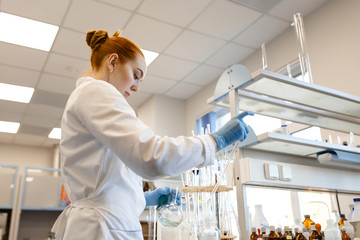 The girl in the lab mixing chemicals. The girl is holding a test tube with chemicals. The photo illustrates science and education.