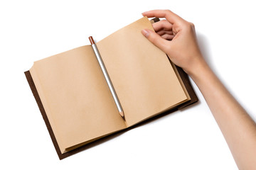 female hand turns over a page of an open craft notepad on which lies a gray pencil on a white background