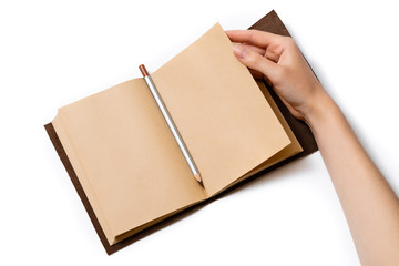 female hand turns over a page of an open craft notepad on which lies a gray pencil on a white background