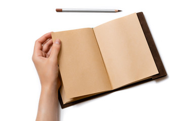 female hand turns over a page of an open craft notepad on which lies a gray pencil on a white background