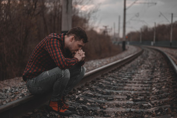 Trendy young man sitting on rails.