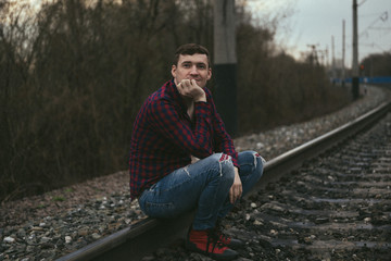 Fototapeta premium Trendy young man sitting on rails.