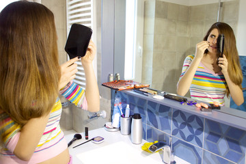 Woman desperate about hair loss in front of mirror in bathroom