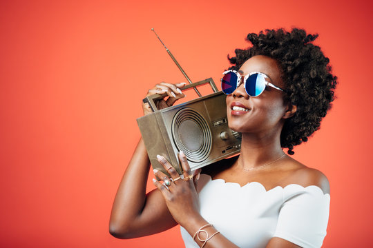 Black girl with sunglasses dancing to a hip song playing from the boombox