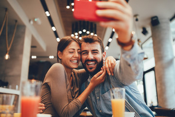 Young happy couple at cafe taking selfie