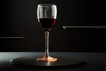 Composition of red wine in glass on black background.
