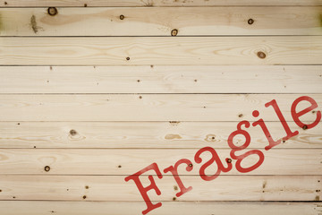 Soft light wood background, surface texture with natural pattern with the red word Fragile