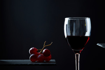 Composition of red wine in glass on black background.