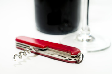 Folding knife with wine opener, glass and wine bottle on a white background