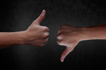 hand dislike sign, giving thumb up and thump down for defeated on black background.