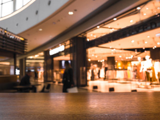 Naklejka premium Blurred image wood table and abstract department store shopping mall center and people background