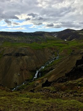 A waterfall runs through a valley in Iceland